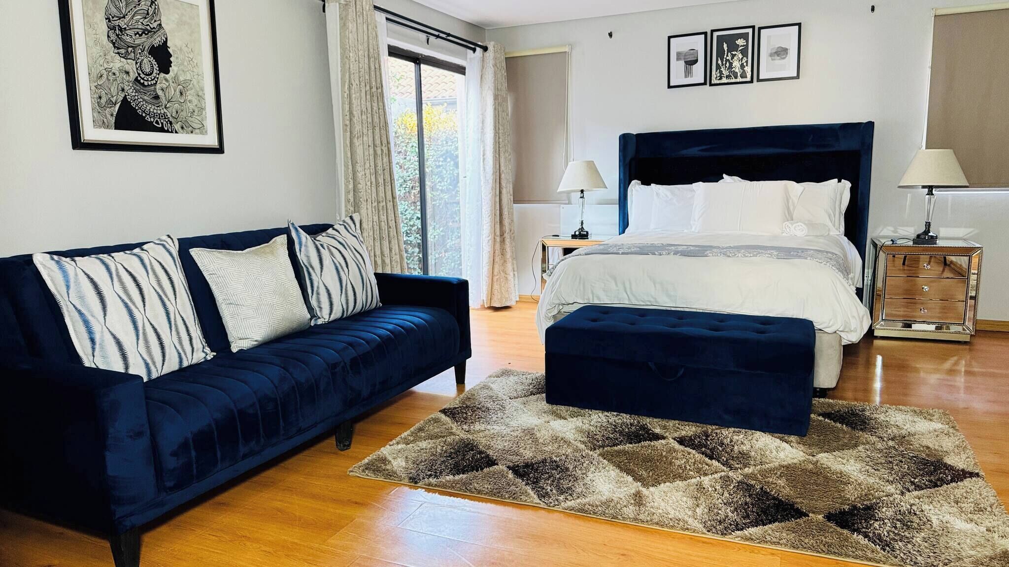 A bedroom with a bed, a sofa, a nightstand, and a rug.