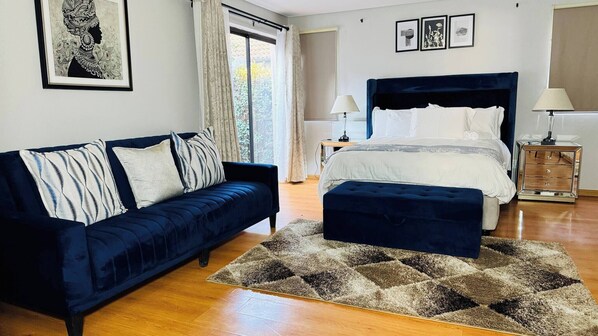 Une chambre à coucher avec un lit, un canapé, une table de chevet et un tapis.