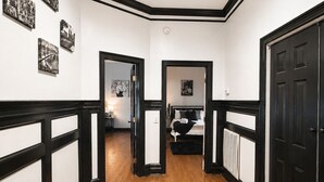Un pasillo con suelo de madera, detalles negros y una cama al fondo.