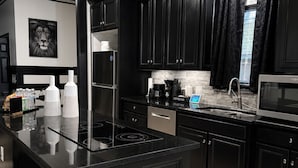 Una cocina moderna con gabinetes negros, una isla central, electrodomésticos de acero inoxidable y una zona de café.
