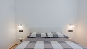 A bedroom with a bed, two wall-mounted lights, and a small table with a remote control. - Vacation home  by Interhome (Krneza)