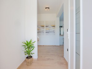 A hallway with a wooden floor, a potted plant, and a wall with abstract paintings. - Vacation home  by Interhome (Krneza)