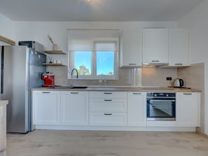 A modern kitchen with white cabinetry, a built-in oven, and a window above the sink. - Holiday Home Bonato with pool by Interhome (Krneza)