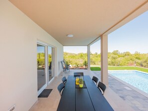 A covered outdoor area with a pool, a table with chairs, and a view of a green landscape. - Holiday Home Bonato with pool by Interhome (Krneza)
