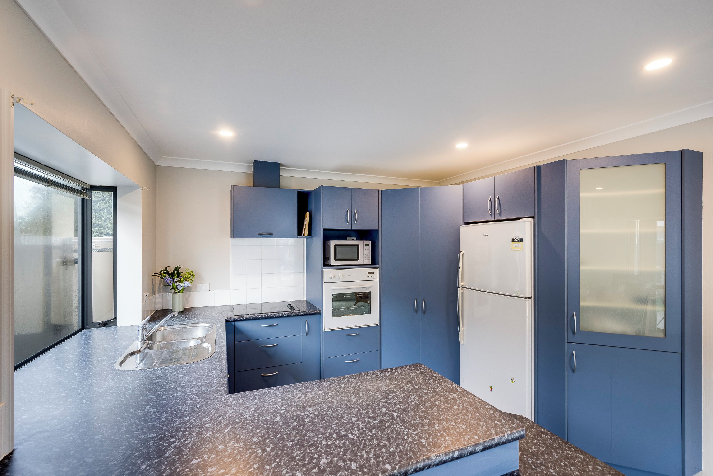 A modern kitchen with blue cabinets, a stainless steel sink, and a built-in oven.