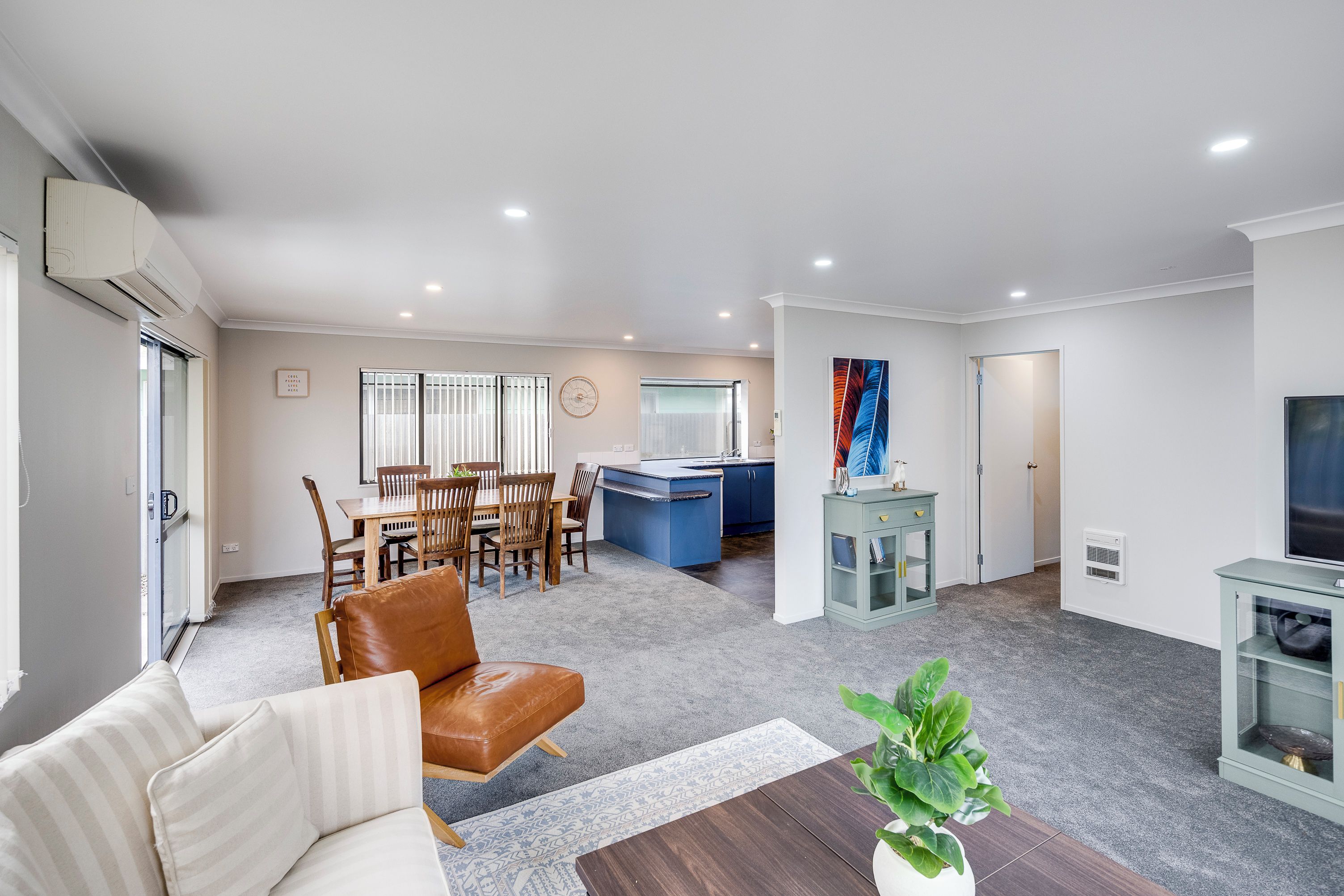 A modern living room with a dining area, a kitchen, and a TV.