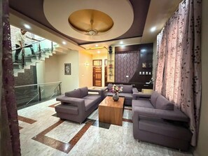 A living room with sofas, a coffee table, and a staircase. - Rameshawram Sukoon Mansion (Varanasi)