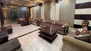 A modern living room with a sectional sofa, a coffee table, and a patterned wall. - Rameshawram Sukoon Mansion (Varanasi)
