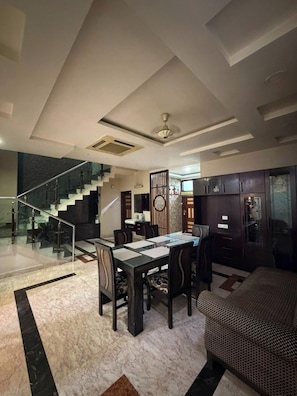A modern interior with a dining area, kitchen, and staircase. - Rameshawram Sukoon Mansion (Varanasi)