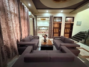 A living room with a sofa set, a coffee table, and a staircase leading to another level. - Rameshawram Sukoon Mansion (Varanasi)