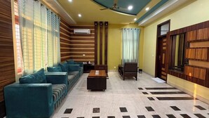 A room with a sofa set, a coffee table, a TV, and a patterned floor.