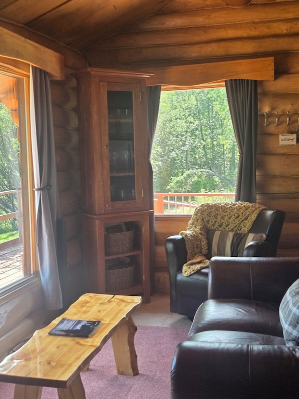 A cozy cabin interior with a wooden cabinet, leather sofa, and a table.