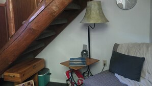 En trappe med træbjælker, et vægur, en lampe, et lille bord med bøger, en pude og et skakspil.