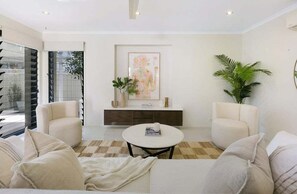 A modern living room with a sofa set, a coffee table, and a decorative console table with plants. - Riviera Road Miami - 4BRM Dual Villa (Gold Coast)