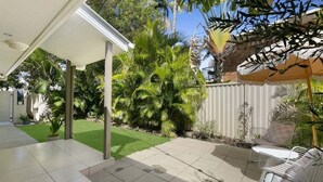 Ein überdachter Patio-Bereich mit Sitzgelegenheit und einem gepflegten Garten.