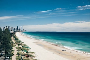 Paesaggio costiero con spiaggia, cielo sereno e una fila di edifici alti.