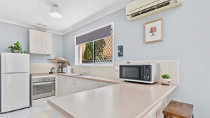 A modern kitchen with a central island, built-in oven, microwave, and a window with a view. - 2BR Paradise at Riviera (Gold Coast)