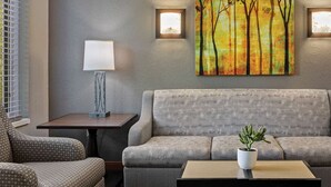 A room with a grey sofa, a small table with a potted plant, and two wall-mounted lamps. -  Spacious 2-bedroom condo in Magical Canmore with fitness room and AC (Canmore)