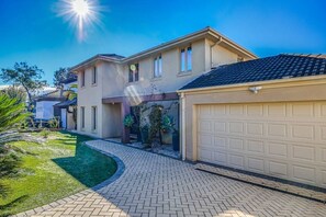 Ein zweistöckiges Haus mit Garage, überdachter Terrasse und gepflegtem Rasen.