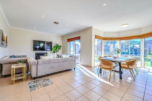 Ein modernes Wohnzimmer mit Sofa, Fernseher und Essbereich mit Blick.