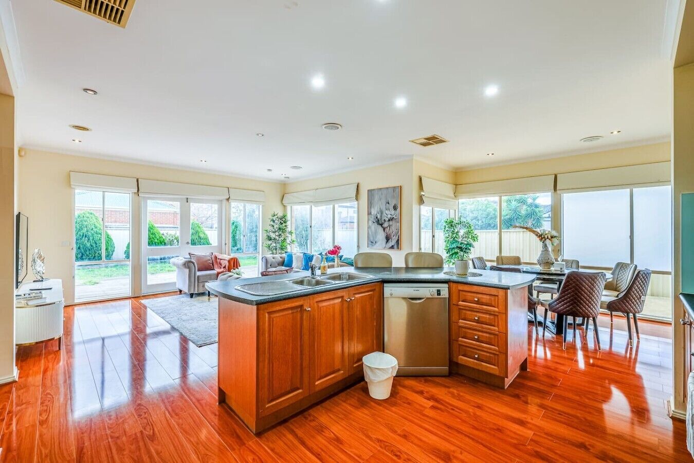A spacious kitchen with a central island, wooden cabinets, and a dishwasher.