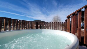 Un jacuzzi en una terraza de madera con cielo despejado.