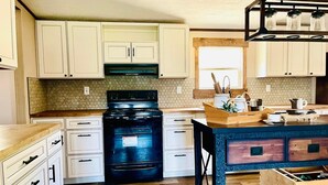 Una cocina con armarios blancos, una estufa negra y una isla de madera con un lavabo.