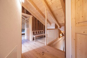Een houten interieur met een trap die naar een hoger niveau leidt, een bank en een deur.