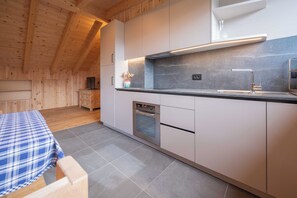 Een moderne keuken met houten balken in het plafond, een inbouwoven en een aanrecht met spoelbak.