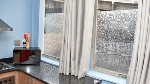 Una cocina con ventana, estufa y un organizador de utensilios.