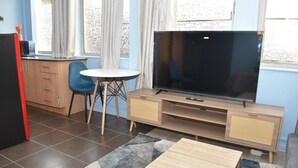 Una sala de estar con televisor, una mesa de comedor y una zona de cocina.