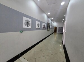 A hallway with tiled flooring, grey walls, and framed pictures on the wall.
