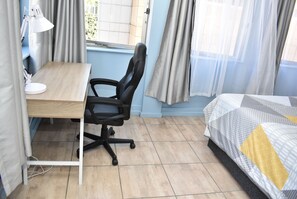 A room with a desk, chair, and bed.