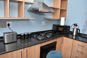A compact kitchenette with a toaster, a kettle, a microwave, and a stove.