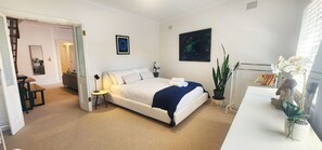 A bedroom with a bed, bedside table, lamp, and a potted plant. - Experience the Best of Sydney's Eastern Beaches - Ocean Views. 3 Bedrooms. (Waverley)