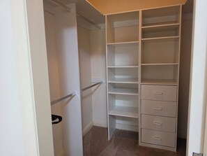 Ein begehbarer Kleiderschrank mit offenen Regalen und Schubladen.