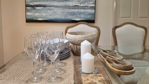 Une table à manger avec plusieurs verres à vin, des assiettes, une bougie blanche et des bols en bois, le tout posé sur un set de table en fibres tressées.