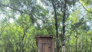 Eine Holzhütte mit Tür und Treppe, umgeben von einem Wald.