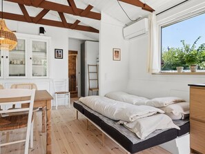 A bedroom with a bed, a window with plants, a wooden ceiling, and a white cabinet. - "Antonie" - 350m from the sea by Interhome (Vejby)