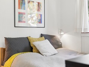 Ein Schlafzimmer mit einem Bett, Kissen, einer Steudecke und einem gerahmten Kunstwerk an der Wand.
