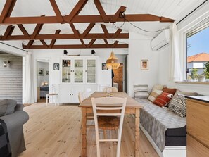 A spacious room with a wooden dining table, a sofa, and a window with a view. - "Antonie" - 350m from the sea by Interhome (Vejby)