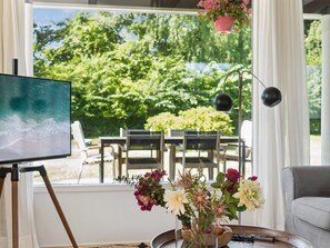 A room with a large window, a painting on a tripod, a table with chairs, a vase with flowers, and a couch. - "Antonie" - 350m from the sea by Interhome (Vejby)