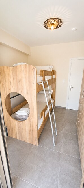 A bunk bed with a ladder, a circular window, and a door. - Zidros Apartments Ground Floor Apartment 2 (Sfakaki)