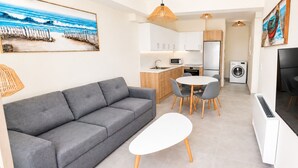 A compact living space with a sofa, a round dining table, and a flat-screen TV. - Zidros Apartments Ground Floor Apartment 2 (Sfakaki)