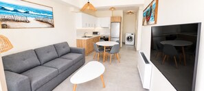 Ein kompakter Wohnraum mit Sofa, rundem Esstisch und Flachbildfernseher.