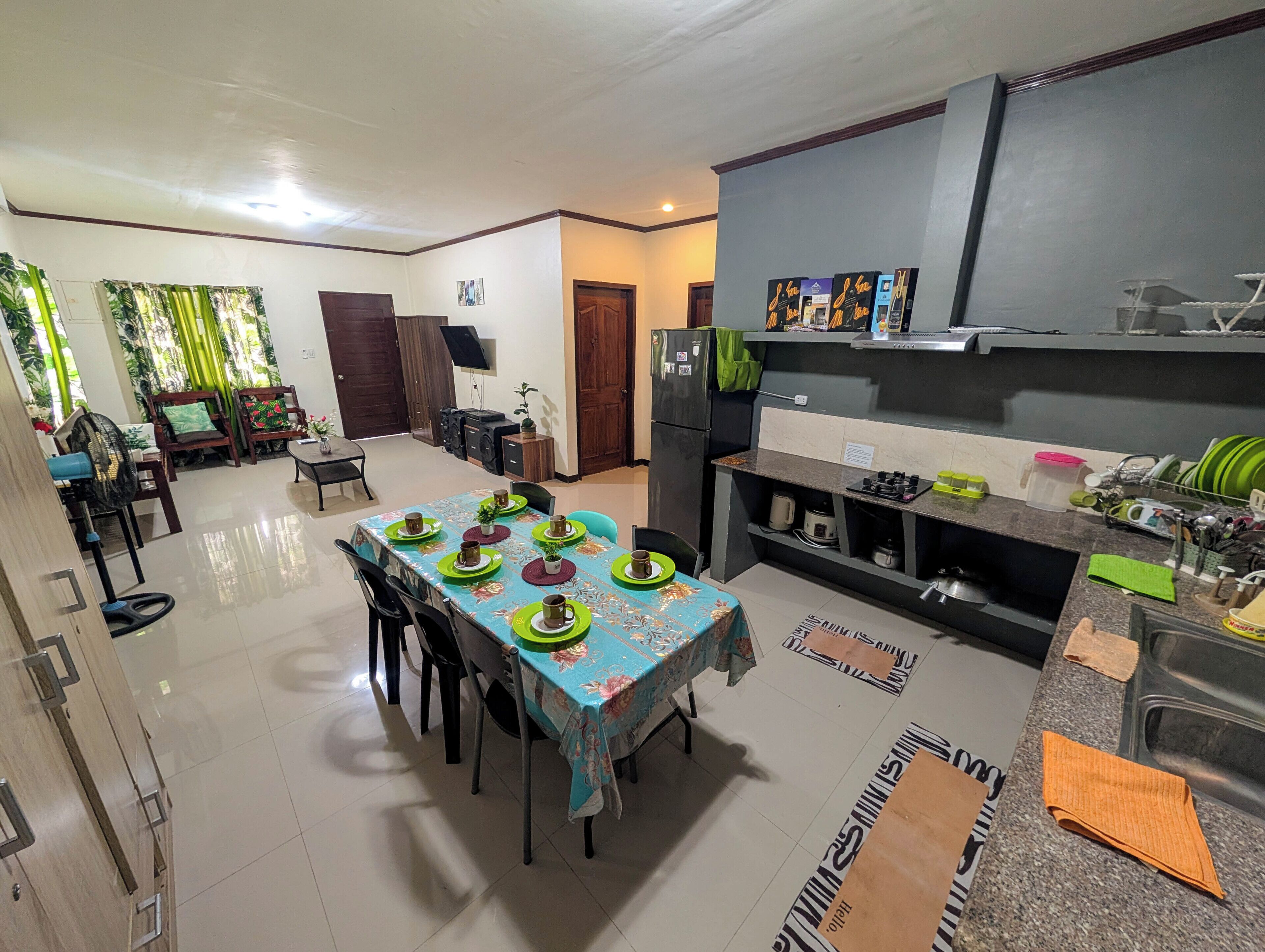 A dining area with a table set for four, a kitchen with modern appliances, and a living area with a sofa and a television.