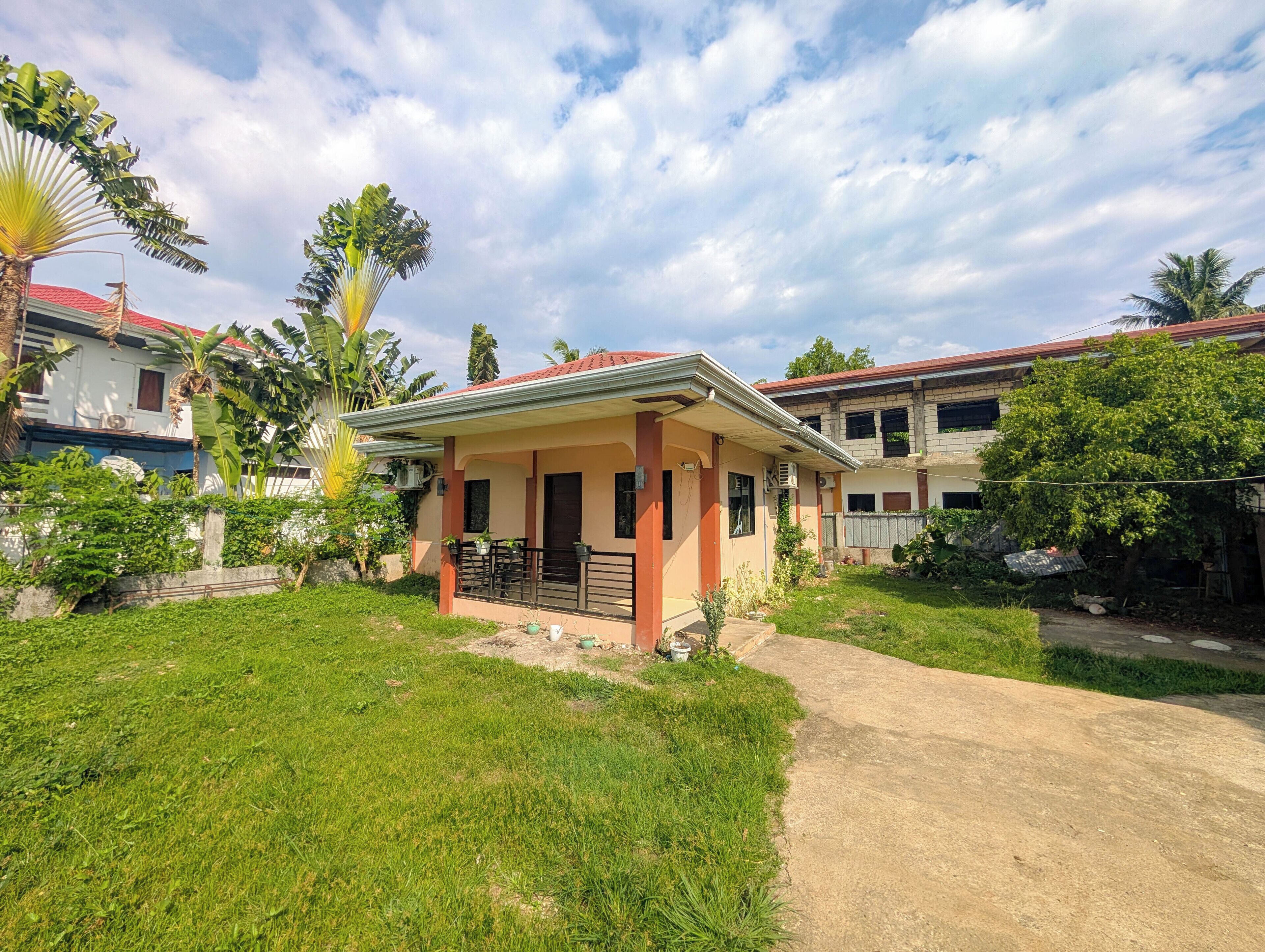 A residential area with houses, a paved driveway, and a grassy lawn.