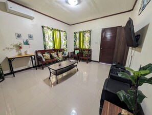 Una sala de estar con sofá, sillones, una mesa de centro y televisor.