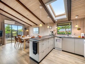 A modern kitchen with a central island, wooden ceiling beams, and large windows. - "Clea" - 250m to the fjord by Interhome (Skjern)
