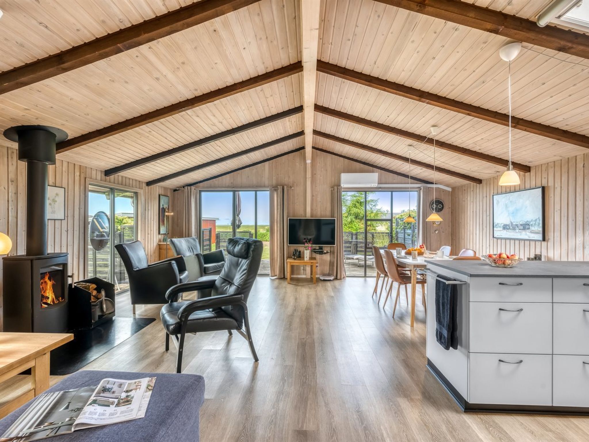 A spacious living area with a fireplace, leather chairs, a dining table, and a kitchen with a large island.